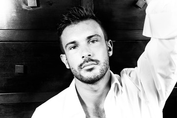 Portrait of good looking man with beard and open shirt looking at camera