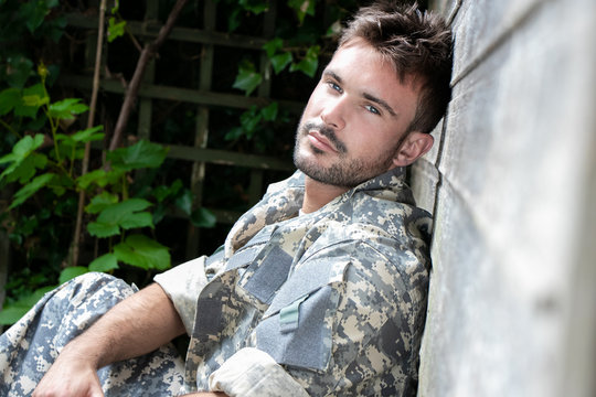 Portrait of attractive male soldier wearing camouflage uniform looking at camera