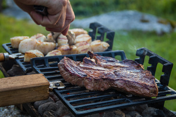 Steak and Scallops grilling on a hibachi as hot charcoal develops smoke and flames on a summer night