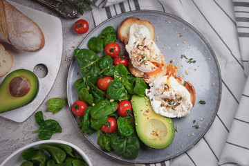 Toasts with avocado and poached egg, tomatoes and spinach, On a light gray background, Fresh morning breakfast