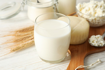 Spikelets of wheat, dairy products and board on white wood background, closeup