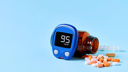 Glucose meter displaying ideal blood sugar range, colorful medical pills spilling out of drug...