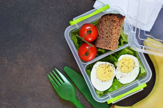 Lunch box with egg, tomato, salad and sandwich. View from above.