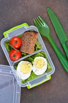 Lunch box with egg, tomato, salad and sandwich. View from above.