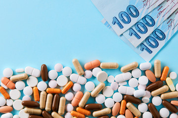 Hundred Turkish Lira bills over the medical pills. Expensive medicine and healthcare industry concept. Overhead macro view with copy space.