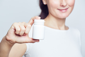 Woman holding white plastic pill bottle selective focus closeup