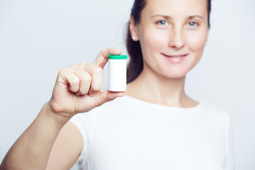 Woman holding white plastic pill bottle selective focus closeup