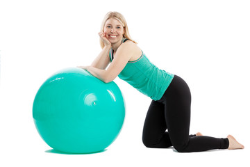 Smiling young woman in sportswear doing exercises with fitness ball. Isolated over white background.