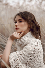 Autumn beauty portrait of a beautiful girl in a field in the grass rays of the sunset. Lifestyle woman with natural makeup on nature. Romantic autumn mood, long tall grass in the meadow