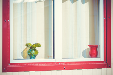 Window with red frame and vases placed on windowsill.