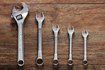 Set of wrenches tiered on wooden table background.