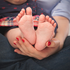 Closeup of the feet of a baby girl little girl in the arms of mom.