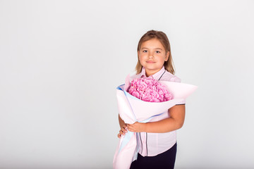 Cute adorable girl holding a bouquet of pink flowers for school teacher of lovely mom on isolated white background. Childhood, happiness, school concept