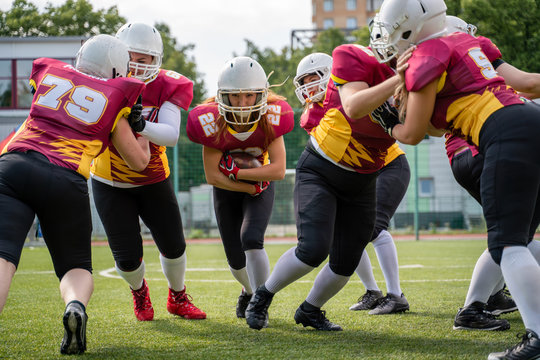 Full-length image of athletes women playing american football on green lawn