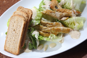 Caesar salad served with roast chicken, fresh lettuce, toasted garlic bread, Dijon mustard, Parmesan cheese and black pepper.