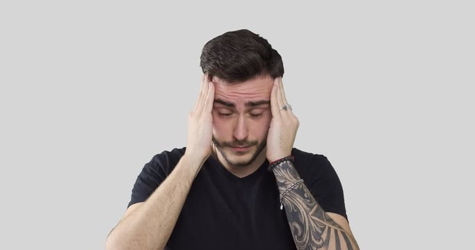 Handsome young man suffering from headache over white background