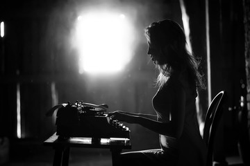 Fototapeta na wymiar A girl prints on an old typewriter
