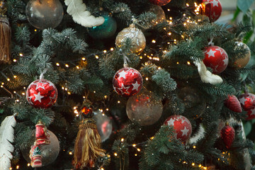 Obraz na płótnie Canvas Close-up white and red christmas balls with a golden garland on christmas tree branches, selective focus