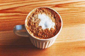 Cup of cappuccino on a wood table In natural light above view