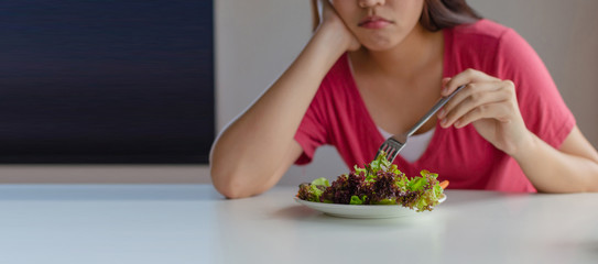panoramic banner. asian young pretty woman bored emotion and refuse for eating fresh green vegetables salad on table for good health at home, nutrition, weight loss, diet and healthy food concept