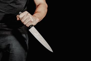 Man's hand holds a knife on black background. topics of violence and murder. thief, killer, rapist,...