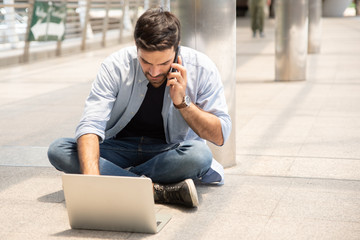 Obraz premium Full Length Of Businessman Using Laptop While Sitting On Footpath