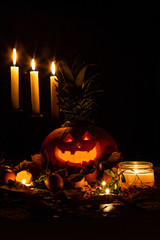 halloween jack-o-lantern pumpkin and candles on autumn leaves