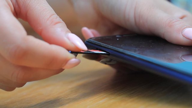 female hand inserts a sim card into the phone