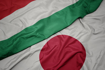 Obraz premium waving colorful flag of japan and national flag of hungary.