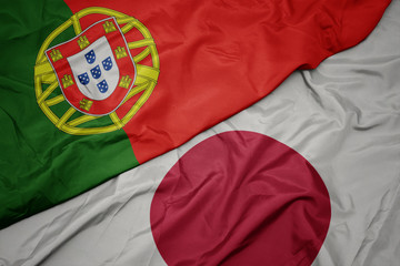 waving colorful flag of japan and national flag of portugal.
