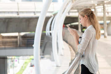 Fototapeta premium Businesswoman Using Phone On Walkway Bridge In City