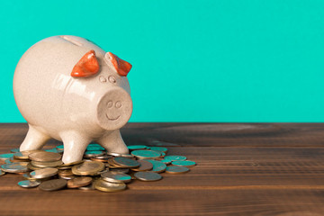 Piggy Bank and a few coins on the wooden table. Close up. The concept of saving money. Selective focus.