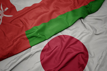 waving colorful flag of japan and national flag of oman.