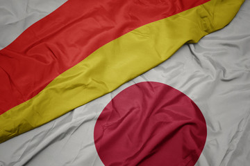 waving colorful flag of japan and national flag of south ossetia.