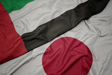 waving colorful flag of japan and national flag of united arab emirates.