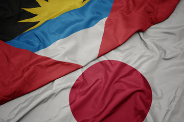 waving colorful flag of japan and national flag of antigua and barbuda.