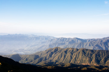 Mountain landscape in the fog with clear blue sky.