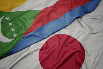 waving colorful flag of japan and national flag of comoros.