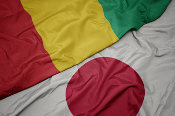 Fototapeta premium waving colorful flag of japan and national flag of guinea.