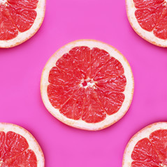 Fresh pieces of grapefruit on a pink background.