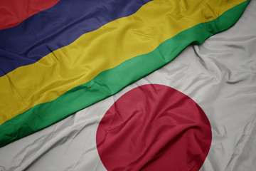 waving colorful flag of japan and national flag of mauritius.