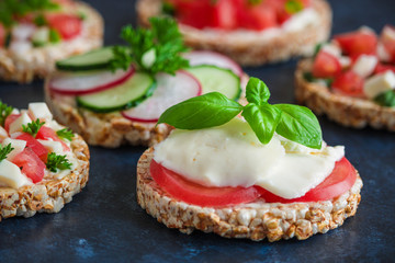 homemade healthy snack rice  cakes with mozzarella tomatoes basil and chopped vegetables close up