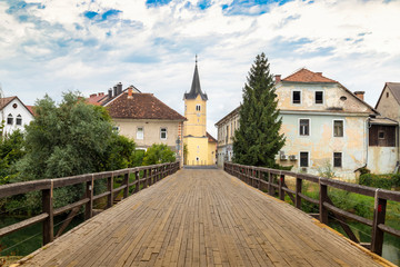 Fototapeta na wymiar Kostanjevica na Krki, the wooden bridge on the river Krki at the entrance of the village