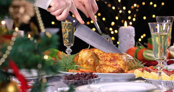 Woman hands carving roasted chicken on Christmas dinner near Christmas tree. 4k