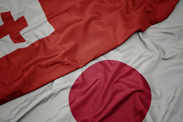 waving colorful flag of japan and national flag of Tonga.