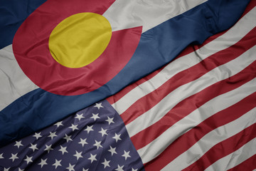Obraz premium waving colorful flag of united states of america and flag of colorado state.