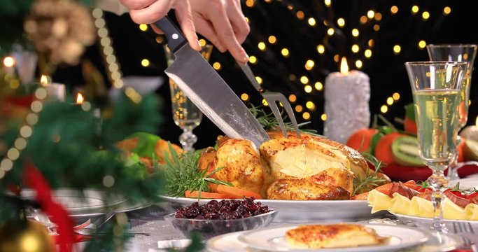 Woman hands carving roasted chicken on Christmas dinner near Christmas tree. 4k