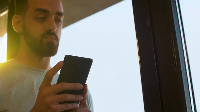 Selective focus on manager phone near a big window in warm sunset light. Slow motion shot