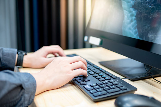 Male hands typing computer keyboard using material simulation software for home interior design in furniture store.