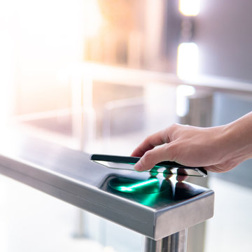 Male hand using smartphone to open automatic gate machine in office building